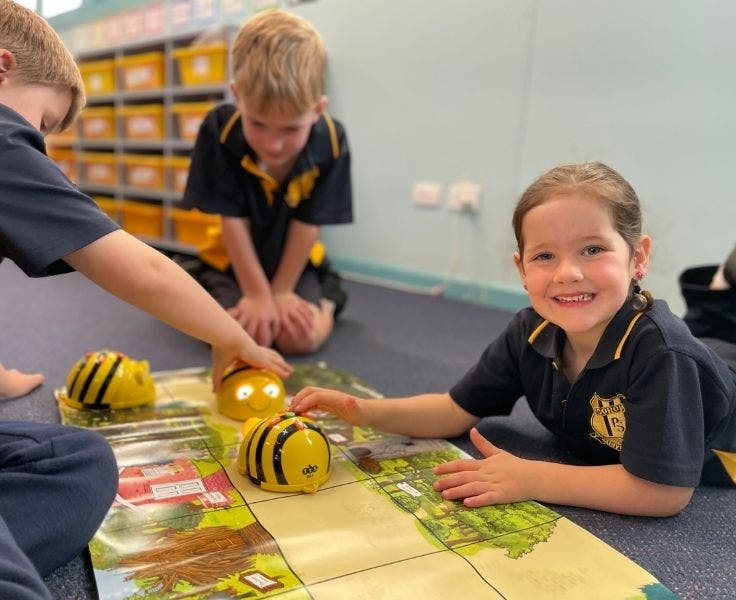 3 students coding bee bots on the floor in the technology room.
