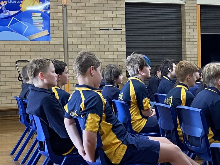 Students sitting in the hall, listening to the guest speaking.