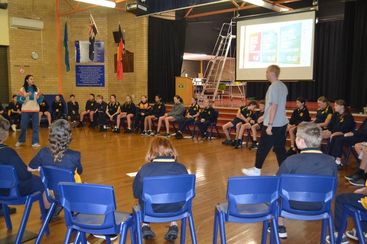 students sitting in a giant circle in the hall watching the presenters in the centre.