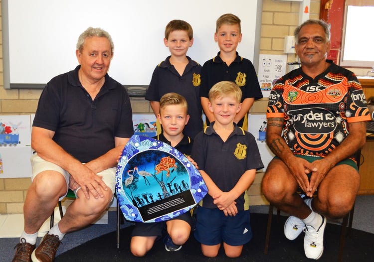 4 students and 2 quests posing for a photo showcasing one of the indigenous artworks.
