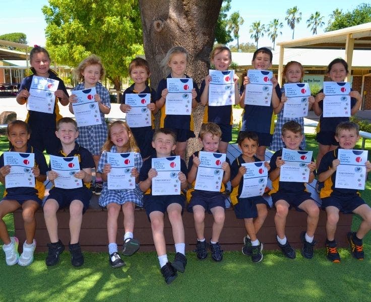 a large group of primary students holding Premier's Reading Challenge Certificates.