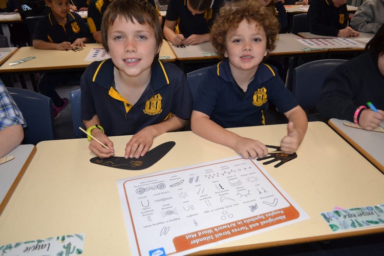 2 students working on their indigenous craft designs.