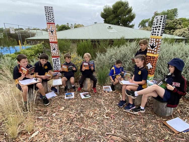 8 students sitting in our yarning circle reading some of the resources purchased.