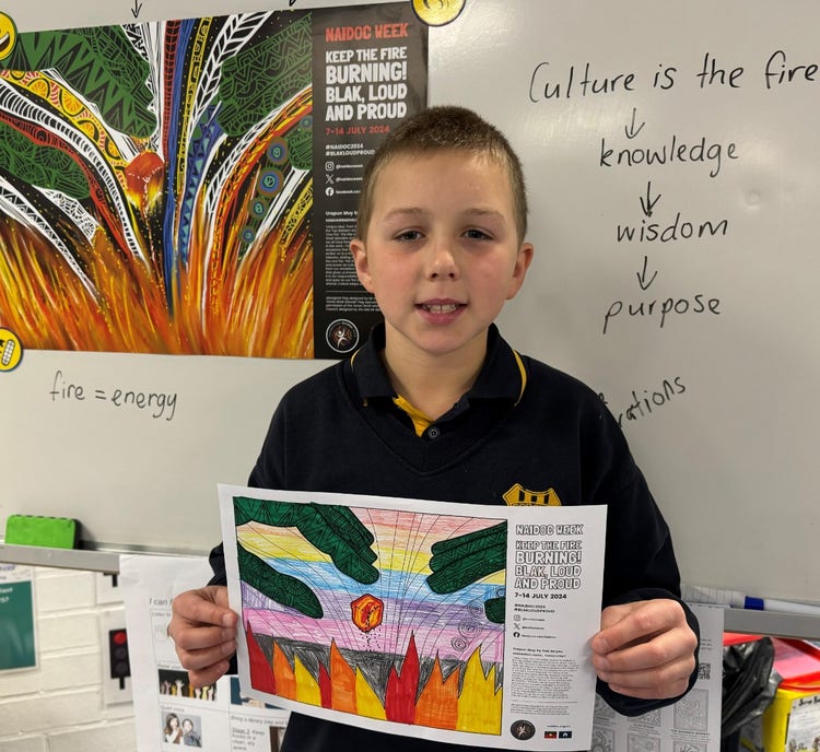 One student holding his Indigenour artwork while smiling at the camera.
