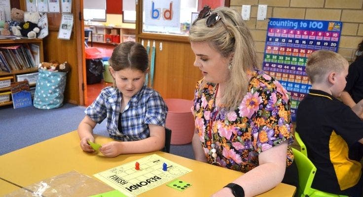 a teacher working with a student in the classroom.