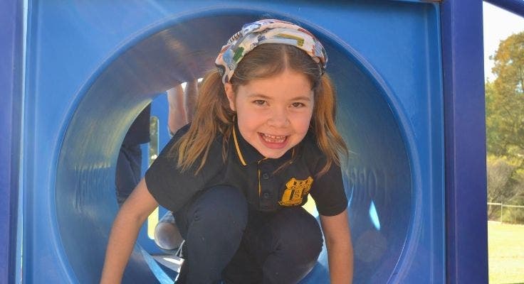 a student coming out of the tunnel on the play equipment.
